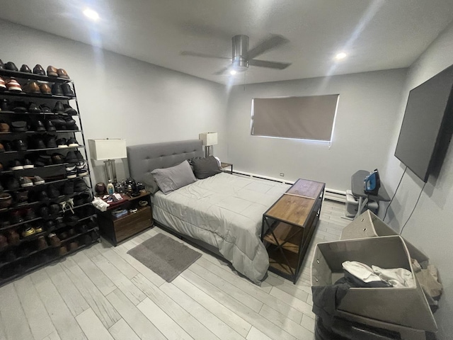 bedroom with wood finished floors, a baseboard heating unit, a ceiling fan, and recessed lighting