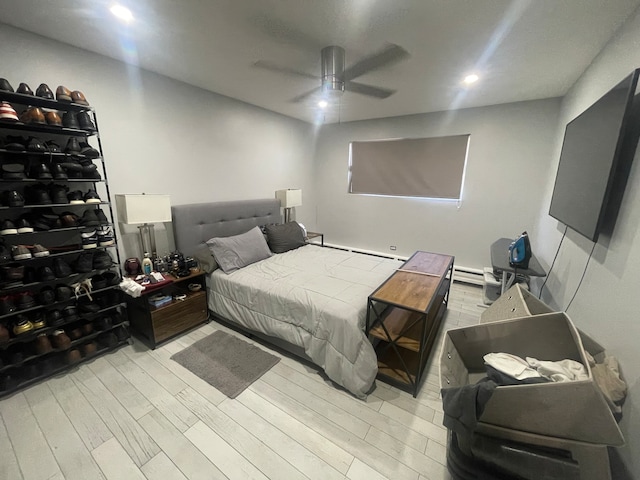 bedroom featuring a baseboard heating unit, light hardwood / wood-style flooring, and ceiling fan