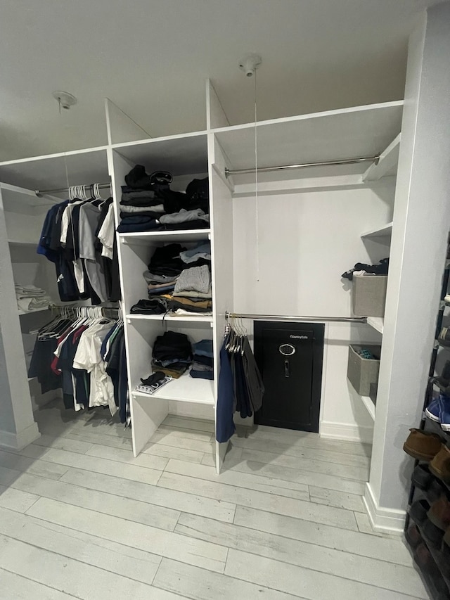 walk in closet with light hardwood / wood-style floors