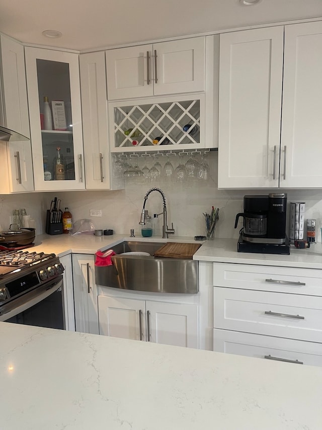 kitchen featuring white cabinetry, wall chimney exhaust hood, sink, and stainless steel stove