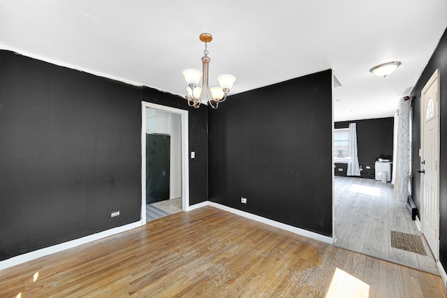 spare room with light hardwood / wood-style flooring and a notable chandelier