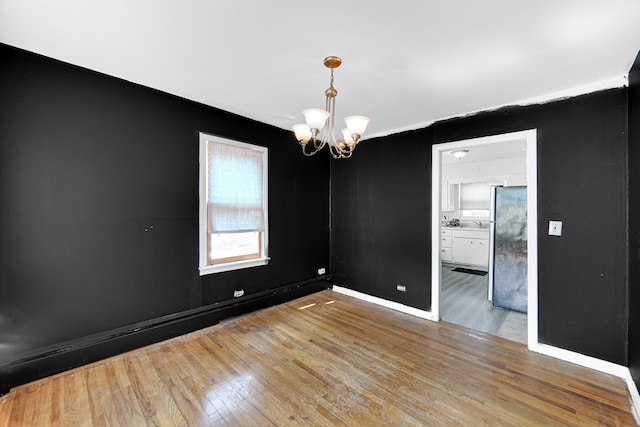 spare room with light hardwood / wood-style flooring and an inviting chandelier