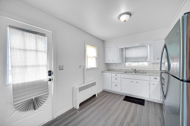 kitchen featuring white cabinets, stainless steel fridge, radiator, and light hardwood / wood-style flooring