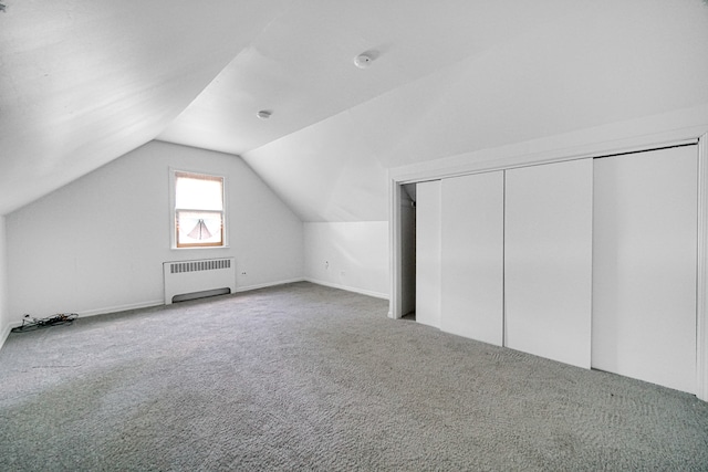 additional living space with lofted ceiling, carpet flooring, and radiator