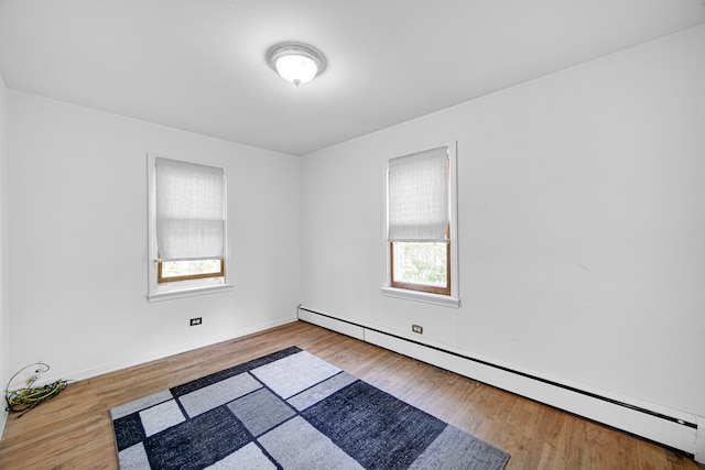 empty room with a baseboard heating unit and hardwood / wood-style flooring