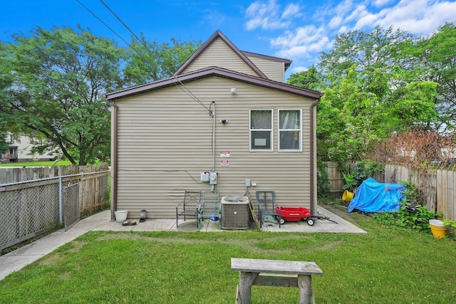 rear view of property with central AC unit, a patio area, and a lawn