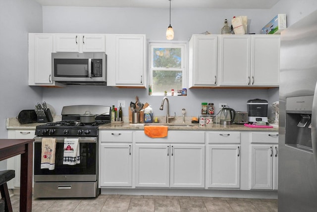 kitchen with white cabinetry, stainless steel appliances, decorative light fixtures, and light stone countertops