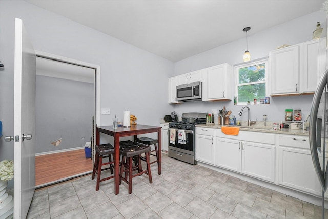 kitchen with stainless steel appliances, white cabinets, and decorative light fixtures