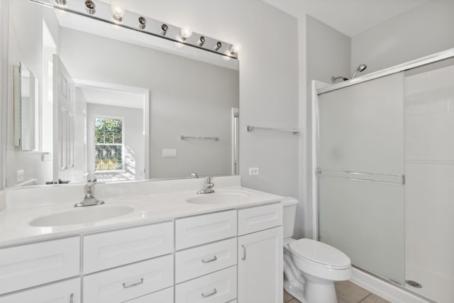 bathroom featuring toilet, a shower with shower door, vanity, and tile patterned flooring