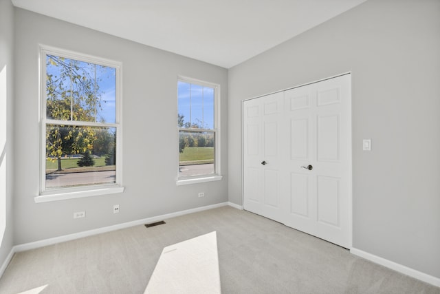 unfurnished bedroom with a closet and light carpet