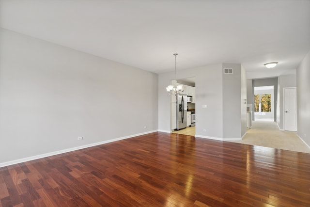 unfurnished room with a notable chandelier and light wood-type flooring