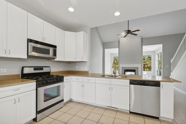 kitchen with sink, kitchen peninsula, white cabinetry, stainless steel appliances, and lofted ceiling