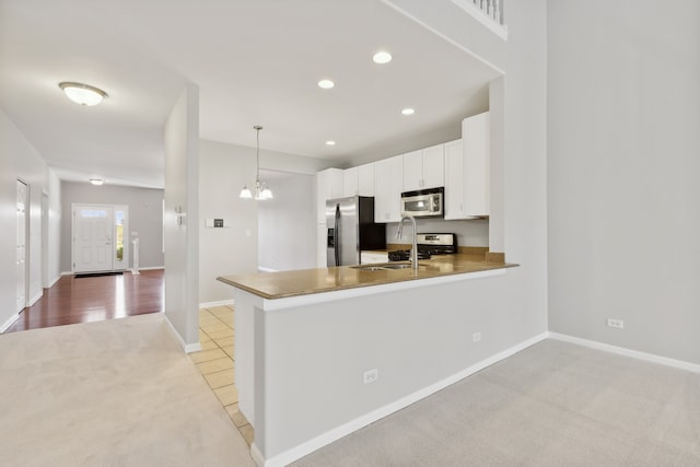 kitchen featuring light carpet, kitchen peninsula, appliances with stainless steel finishes, white cabinetry, and pendant lighting