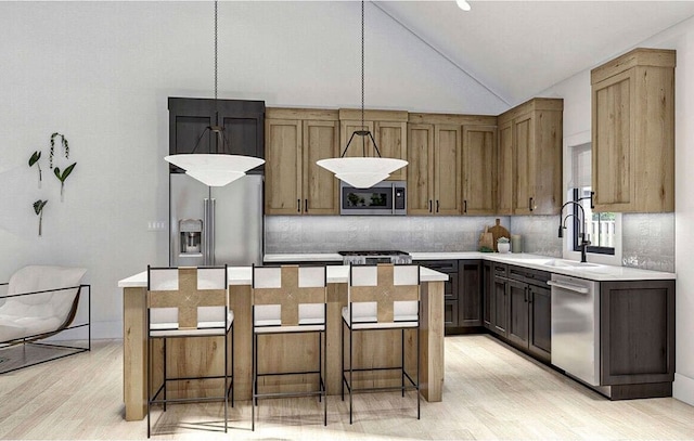 kitchen with decorative light fixtures, a center island, a kitchen bar, light hardwood / wood-style floors, and appliances with stainless steel finishes