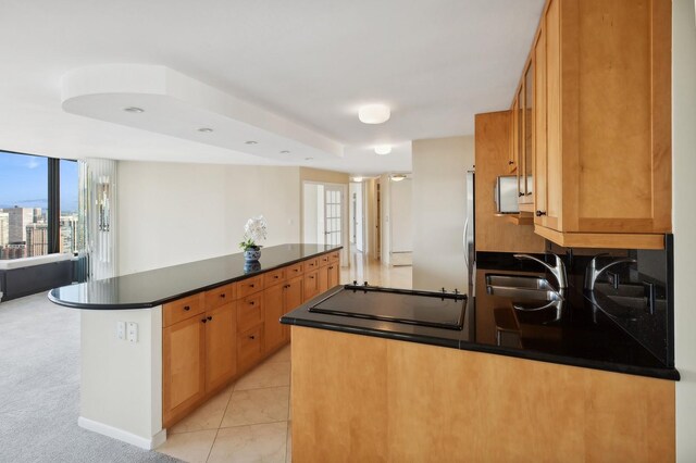 kitchen featuring stovetop, a center island, light carpet, and sink