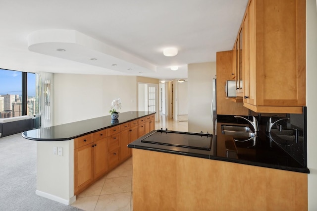 kitchen featuring dark countertops, open floor plan, light tile patterned flooring, a sink, and a peninsula