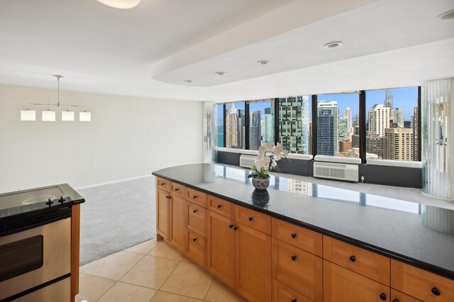 kitchen featuring hanging light fixtures, stainless steel range with electric stovetop, and light colored carpet