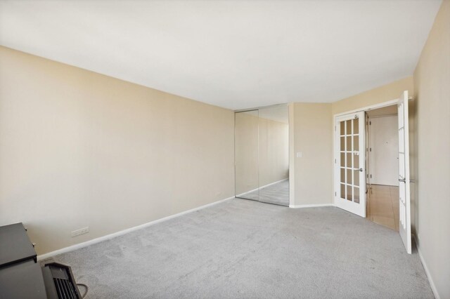 unfurnished bedroom with light colored carpet, a closet, and french doors