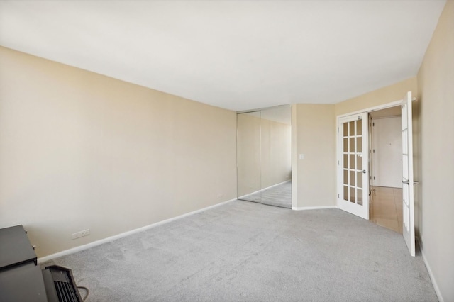 empty room with french doors, light carpet, and baseboards