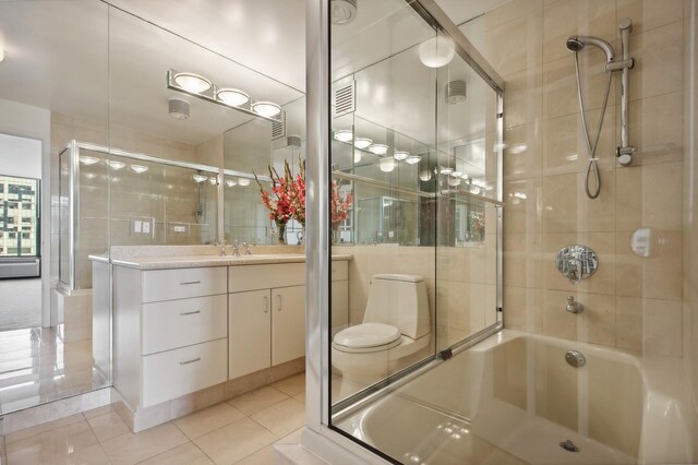 full bathroom featuring vanity, tile walls, bath / shower combo with glass door, toilet, and tile patterned flooring