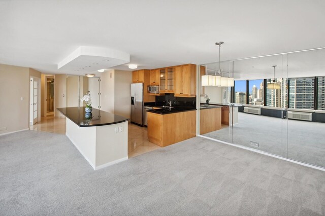 kitchen with a kitchen island, light carpet, hanging light fixtures, and stainless steel appliances