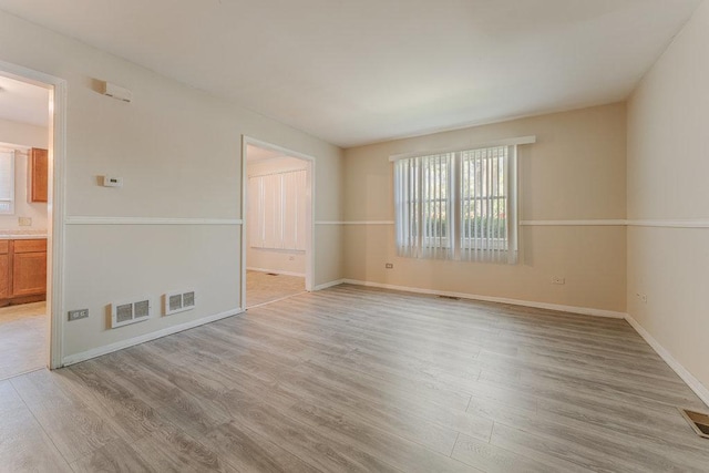 empty room with baseboards, visible vents, and light wood-style floors