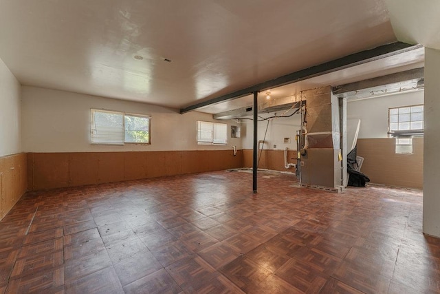 below grade area featuring a wainscoted wall, wood walls, and heating unit