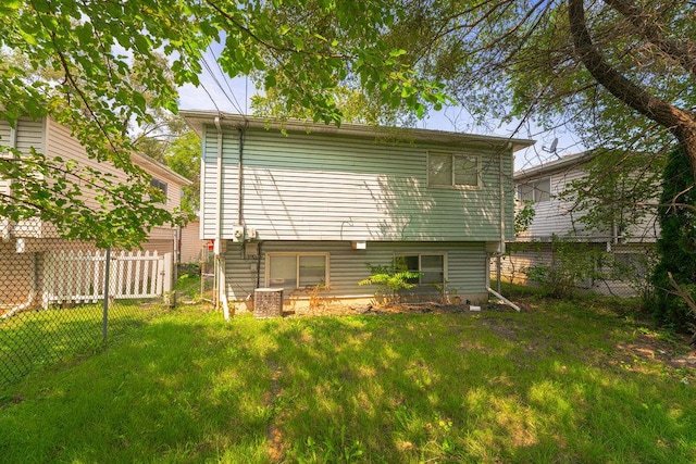 rear view of property featuring a lawn and fence