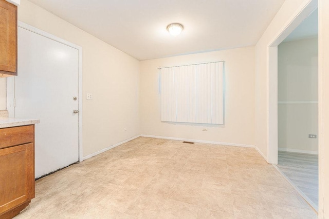 spare room featuring light floors and baseboards