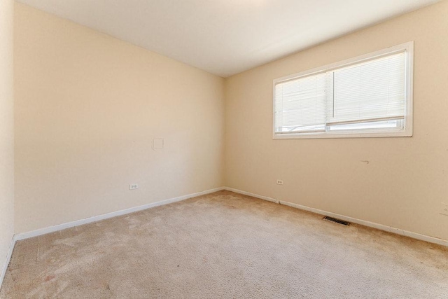 unfurnished room with carpet, visible vents, and baseboards