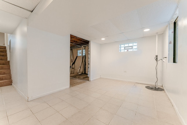 basement featuring light tile patterned flooring and a drop ceiling