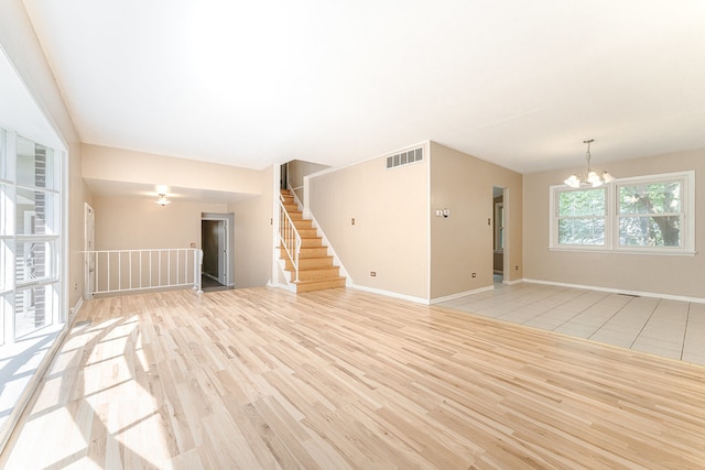 unfurnished living room with light hardwood / wood-style flooring and a notable chandelier