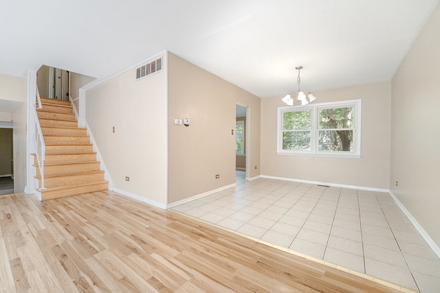 unfurnished room with light wood-type flooring and a chandelier