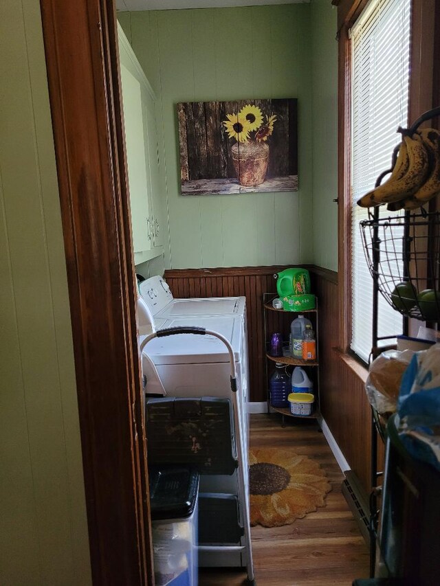 laundry room featuring washing machine and clothes dryer, plenty of natural light, cabinets, and hardwood / wood-style floors