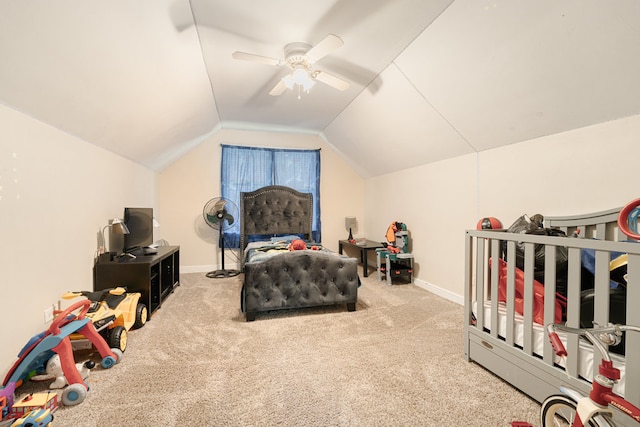 carpeted bedroom with ceiling fan, vaulted ceiling, and a nursery area