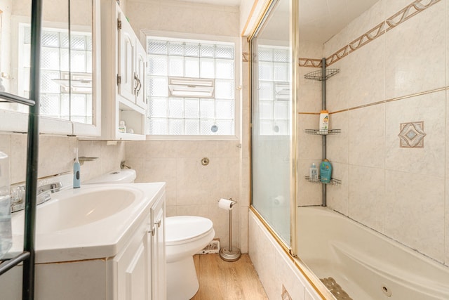 full bathroom with tile walls, wood-type flooring, vanity, and a wealth of natural light