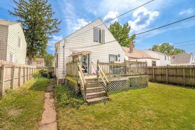 rear view of property featuring a fenced backyard, a deck, and a yard