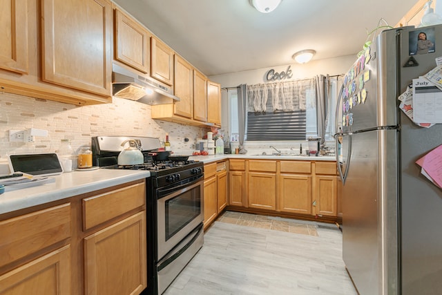 kitchen with light wood-type flooring, tasteful backsplash, range hood, appliances with stainless steel finishes, and sink