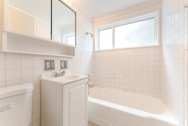 full bathroom featuring tile walls, tiled shower / bath, toilet, vanity, and tasteful backsplash