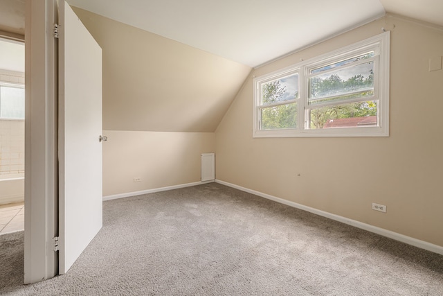 additional living space featuring lofted ceiling and light carpet