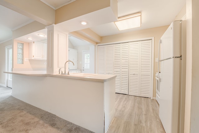 kitchen featuring white refrigerator, sink, light carpet, and kitchen peninsula