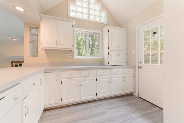 kitchen with lofted ceiling, light wood-type flooring, white dishwasher, and white cabinetry