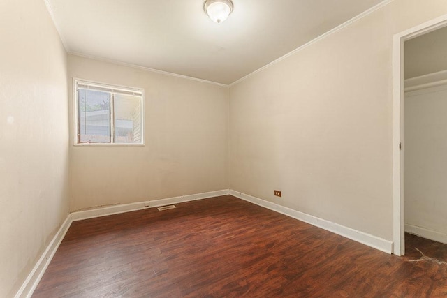 empty room with ornamental molding, dark wood-style flooring, visible vents, and baseboards