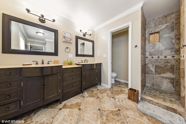 bathroom featuring tile patterned flooring, a tile shower, crown molding, toilet, and dual bowl vanity