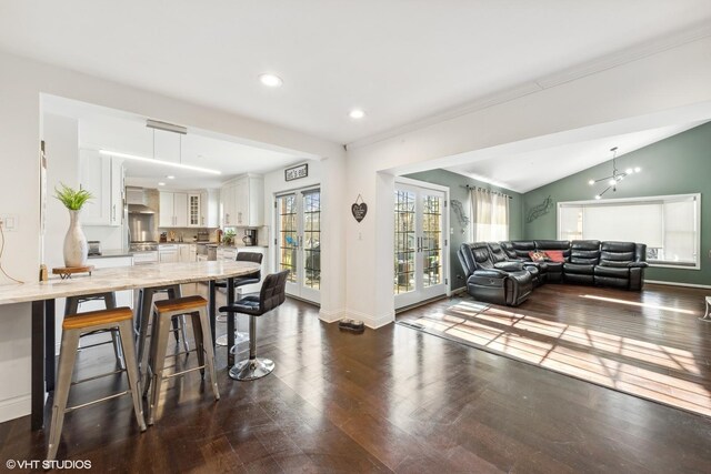 dining room with a notable chandelier, dark hardwood / wood-style flooring, and vaulted ceiling