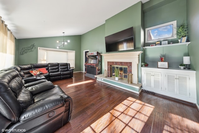 living room with lofted ceiling, a chandelier, a brick fireplace, and wood-type flooring