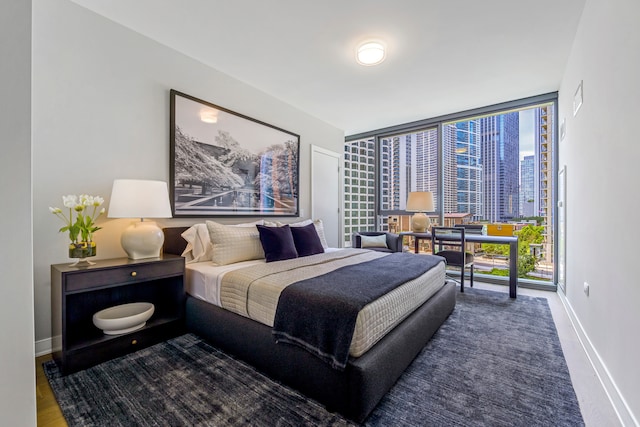 bedroom with floor to ceiling windows and hardwood / wood-style floors