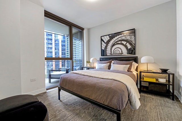 bedroom featuring dark wood-type flooring, expansive windows, and access to outside