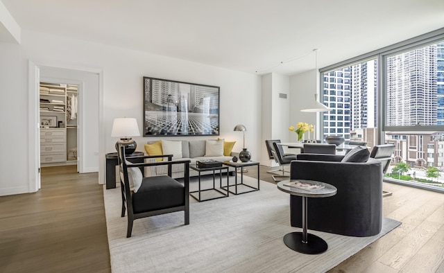 living room with floor to ceiling windows, a wealth of natural light, visible vents, and wood finished floors