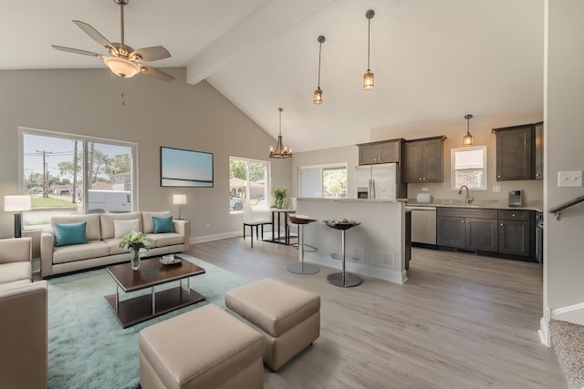 living room featuring high vaulted ceiling, ceiling fan with notable chandelier, beamed ceiling, light wood-type flooring, and sink